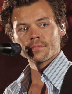 a close up of a person with a microphone in front of him and his shirt on