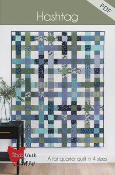 a blue and green patchwork quilt hanging on a wall next to a black table