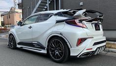 the rear end of a white car parked in front of a building