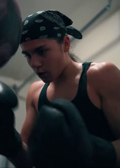 a woman with a bandana on her head and boxing gloves in front of her