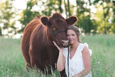 a woman poses with a cow in a field