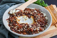 a bowl filled with food sitting on top of a cutting board next to crackers