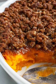 a close up of a pie in a white dish with a spoon on the side