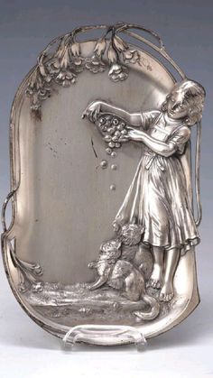 an antique silver plate with a girl holding flowers and a dog on the ground next to it