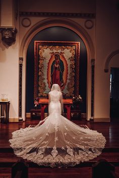 a woman in a wedding dress standing at the alter with her veil blowing in the wind