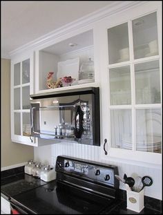 a black stove top oven sitting inside of a kitchen next to white cabinets and glass doors