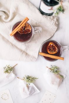 two mugs filled with mulled tea and cinnamon sticks