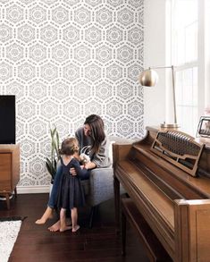 a woman sitting next to a child on top of a couch in front of a piano