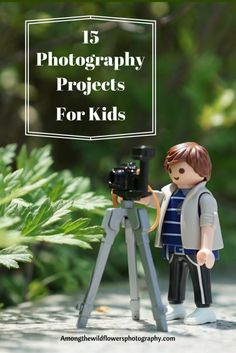 a lego figurine is standing in front of a tripod and holding a camera