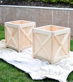 two wooden planters sitting on top of a tarp in the middle of grass