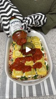 a person pouring ketchup on some food in a dish with other items nearby