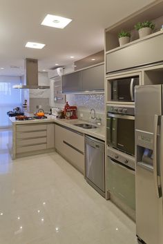 a modern kitchen with stainless steel appliances and marble counter tops, along with white tile flooring