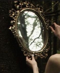 a woman holding a mirror in front of her face