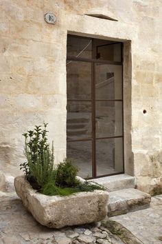 a stone planter sitting in front of a window on the side of a building