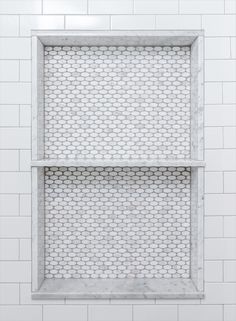 a white tiled wall with two shelves in it