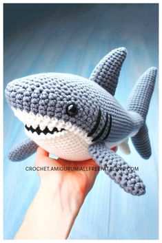 a crocheted stuffed shark is being held up