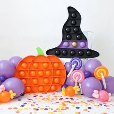 a table topped with lots of balloons and halloween decorations next to a basket filled with candy