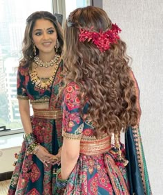 two women dressed in colorful clothing standing next to each other with long hair and jewelry on