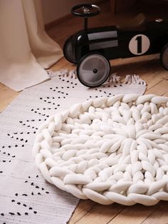 a small toy car sitting on top of a wooden floor next to a white rug