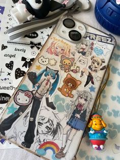 an iphone case with anime stickers on it sitting next to some scissors and other items