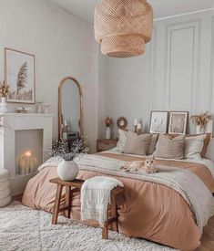 a bedroom with a bed, mirror and fireplace in the corner is decorated in neutral colors