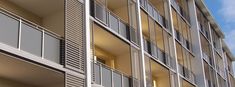 an apartment building with balconies and shutters on the sides, against a blue sky