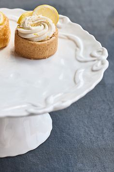 two small pastries on a white plate with lemons and whipped cream frosting