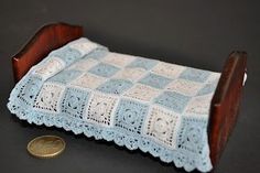 a miniature crocheted tablecloth on a wooden stand with a penny in the foreground