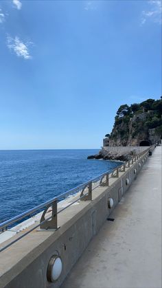 an empty concrete walkway next to the ocean