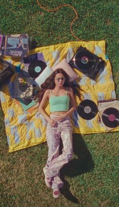 a woman laying on top of a yellow blanket next to record player's equipment