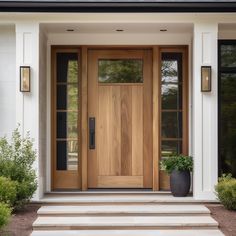 a front door with two planters on the steps and an entry way leading up to it