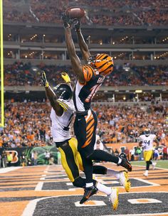 two football players jumping in the air to catch a ball