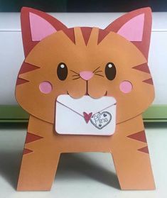 an orange cat with a heart on it's chest is holding a white envelope