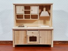 a wooden toy kitchen with an oven, sink and cupboards on the top shelf