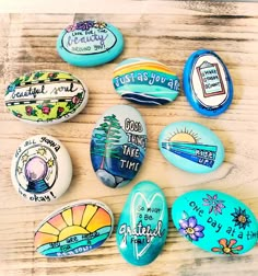 painted rocks with words on them sitting on top of a wooden table next to each other