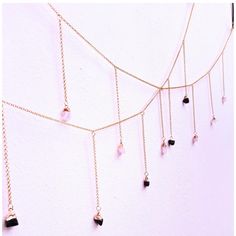 a gold chain with black stones hanging from it's sides on a white wall