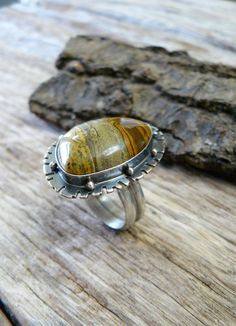 Made with a 18x24 mm natural, painted jasper cabochon, this ring reminds me of Western fields and open roads. The sandy colored gem sits on a 25x34mm base that is adorned with an unique pattern and sterling silver beads. The gem is wrapped in fine silver (.999) and sits on a sterling silver (.925) base. The stone possesses hues of chocolate brown, golden brown and black. The piece has been oxidized and lightly polished giving it great contrast and an industrial vibe. The piece is weighty and ric Artisan Jasper Jewelry With Large Stone, Artisan Jasper Jewelry In Oval Shape, Bohemian Agate Ring With Large Stone, Artisan Oval Jasper Jewelry, Artisan Brown Gemstone Rings, Handmade Jasper Rings As Gift, Handmade Jasper Rings As A Gift, Handmade Jasper Rings For Gift, Southwestern Jasper Jewelry Gift