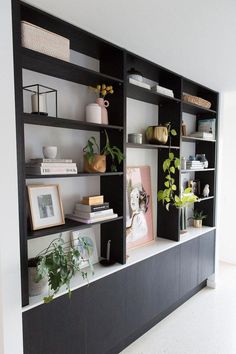 a black bookcase filled with lots of books next to a wall mounted planter