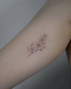 a woman's arm with a small flower tattoo on the left side of her arm