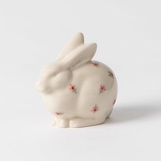 a white ceramic rabbit figurine with pink flowers on it's body and ears