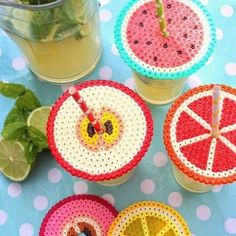 four plastic fruit coasters sitting on top of a table next to lemon slices and mint