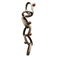 a metal sculpture with two balls hanging from it's sides and an intricate design on the side