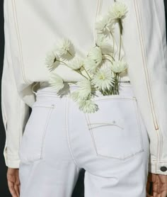 a person wearing white jeans with flowers in the back pocket on their waist and hands