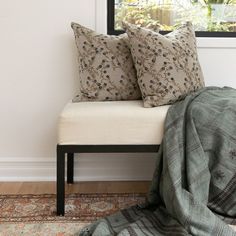 a white bench with two pillows on it and a blanket draped over the seat next to it