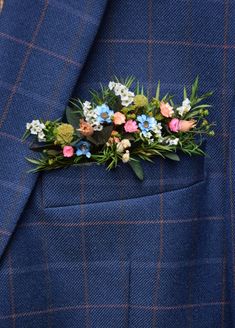 a man wearing a blue suit with flowers on it's lapel flower pin