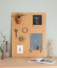 a wooden peg board mounted to the side of a wall next to a potted plant