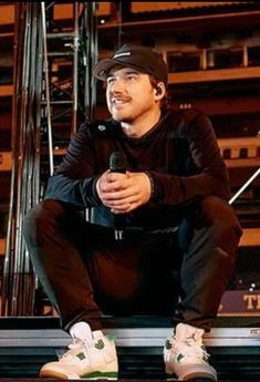 a man sitting on top of a stage holding a microphone