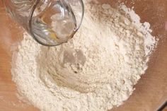 a person pouring flour into a glass bowl