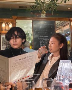 two women sitting at a table with wine glasses and menus in front of them