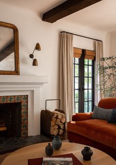 a living room filled with furniture and a fire place in front of a mirror on the wall